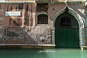 facade, canal, garage, gate, doors, entrance, eroding stone walls, wall sign, arch, water, old historic, decay, Venice Italy