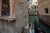 historischer Marienschrein und Gondel in einem engen Kanal in Castello, Lagune von Venedig, Italien
