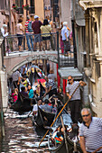 gondola traffic jam, high season, crowds of gondolas  in a narrow canal, old walls, Venice, Veneto, Italy