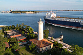 Freighter passes the old Alberoni lighthouse and the pilot station at the Malamocco exit, end of the Lido, Lagoon, Lido, background is MOSE, Venice, Adriatic Sea, Italy