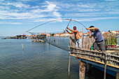 Fishermen with bilanciono nets on a traditional casone, shelters on stilts, Pellestrina, Island, lagoon, Venice, Italy