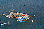 Aerial photo of fishermen's traditional casone, fishing boats and shack on stilts, Pellestrina, Island, lagoon, Venice, Italy
