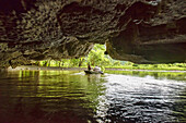 traveling through a cave on the Tam Coc River in Ninh Binh, Vietnam.