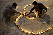 'India, Uttar Pradesh, Varanasi, Dev Deepawali festival, Hindu devotees lighting ''Om'' shaped oil lamps.'