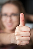 Pretty woman with smiles on thumb giving thumbs up.