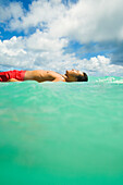 Hawaii, Oahu, Lanikai, Young Japanese Man Lying On Surfboard In The Ocean.