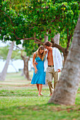 Hawaii, Oahu, Waikiki, Kapiolani Park, Couple Walking In A Tropical Setting.