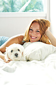 Hawaii, Kauai, Attractive Young Redheaded Woman Models In Bed With Her Puppy.