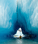 Sea Kayaker Paddles Through An Ice Cave Amongst Giant Icebergs Near Bear Glacier In Resurrection Bay Near Seward, Alaska