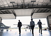 'Three businessmen entering airplane hangar; Langley, British Columbia, Canada'