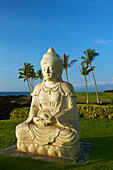 'Statue of Buddha with a view of palm trees and ocean in the background; Kauai, Hawaii, United States of America'