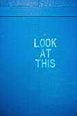 'Words on a blue wall saying look at this; London, England'