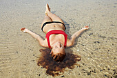Hawaii, Kauai, A redheaded woman laying in the water.