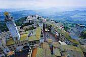 'Fog covers the distant hills with a high angle view of the city; San Gimignano, Tuscany, Italy'