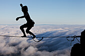 Silhouette of professional highliner Hayley Ashburn standing up on a highline above the clouds atop Mount Tamalpais