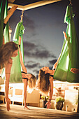 Drei junge Frauen machen Aerial Yoga.