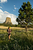 A woman hiking with her backpack below Devil's Tower in Devil's Tower National Monument, Wyoming.