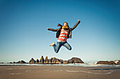 Young woman jumping into the air over Seal Rock Beach, Oregon.