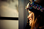 Portrait of a female snowboarder riding the gondola in the sunlight on Whistler mountain.