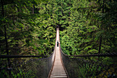 A tourist poses for a picture on the Lynn Canyon Suspension Bridge near Vancouver, Canada.