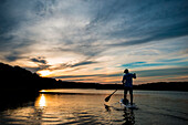 A man paddle boarding in the evening in Kittery, Maine.