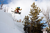 A male backcountry skier with a packpack on catches air off a cornice in the Beehive Basin near Big Sky, Montana.