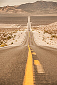 The road that leads to Death Valley from Beatty is lost on the horizon in the desert plain. Beatty, Nevada.