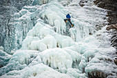 Man lead climbing an ice fall in the middle of a snow storm in Argenti?®re, Chamonix, France.