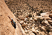 A female climber starts the dike traverse on Sidewinder (5.10b) in Joshua Tree National Park, California.