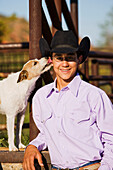 Agriculture - A young cowboy poses while his dog licks his ear / Childress, Texas, USA.