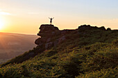 On top of the world, visitor enjoys sunset on Curbar Edge with arms aloft, Peak District National Park, Derbyshire, England, United Kingdom, Europe