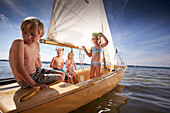 Children in a sailing boat on lake Starnberg, Upper Bavaria, Bavaria, Germany