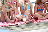 Girls sitting on a jetty while eating ice cream, lake Starnberg, Upper Bavaria, Bavaria, Germany