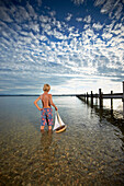 Junge mit einem Spielzeugsegelboot steht im Starnberger See, Oberbayern, Bayern, Deutschland