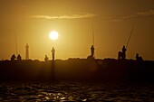 Fishermen on a pier in Rabat at sunset, Morocco