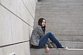 Young woman sitting on a staircase, Munich, Bavaria, Germany