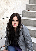 Young woman sitting on a staircase looking at camera, Munich, Bavaria, Germany