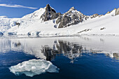 Calm seas reflect snow-capped mountains, Orne Harbor, Antarctica.