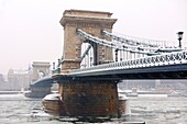 South side of the Szechenyi lánchíd Chain Bridge in the winter snow looking towards the castle district Budapest Hungary.