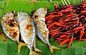 two head fish bbq and chilli bbq on banana leaves , for sale at klong toei market , bangkok , thailand