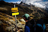 Hiker looking at a signpost, ascent to Bremer Hut (2413 m), rear of Gschnitz Valley, Stubai Alps, Tyrol, Austria