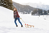 Young woman pulling a sled, Spitzingsee, Upper Bavaria, Germany