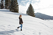 Junge Frau geht im Schnee spazieren, Spitzingsee, Oberbayern, Bayern, Deutschland
