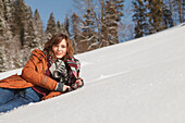Young woman lying in snow, Spitzingsee, Upper Bavaria, Germany
