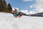 Two young women downill sledding, Spitzingsee, Upper Bavaria, Germany