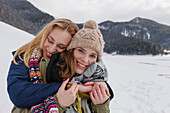 Two young women embracing, Spitzingsee, Upper Bavaria, Germany