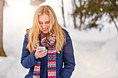 Smiling young woman holing a smart phone, Spitzingsee, Upper Bavaria, Germany