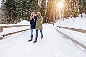 Two young women walking in snow, Spitzingsee, Upper Bavaria, Germany