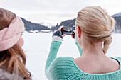 Young women taking a smart phone picture, Spitzingsee, Upper Bavaria, Germany