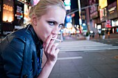 Woman smoking at night, New York City